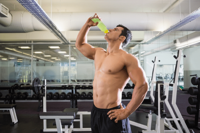 MAN DRINKING ENERGY DRINK AFTER WORKOUT AT GYM